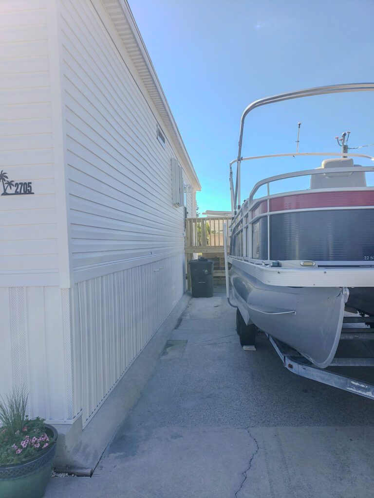 Side view of a mobile home with boat before covered metal carport installation project by experienced carport installation company in Southwest Florida | Sun Control Aluminum & Remodeling